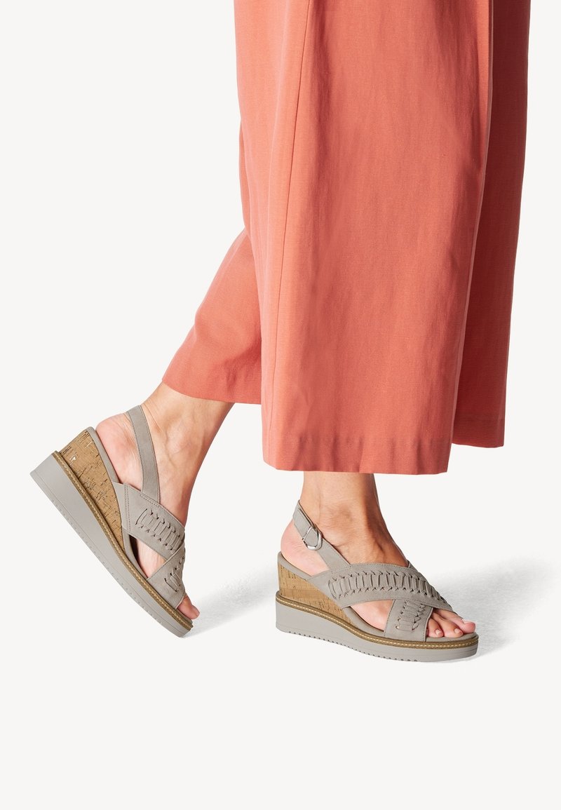 Grijze wig-sandalen met een kurk-textuur hak en uitsnijdingen. Verstelbare enkelband en een gestructureerde rubberen zool. Draag met koraalkleurige wijde broek.