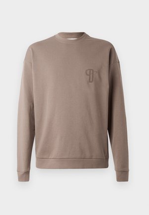 Rjav pulover z okroglim ovratnikom, dolgimi rokavi in rebrastimi manšetami. Ima mali vezeni logotip na prsih. Narejen iz mehke bombažne tkanine.