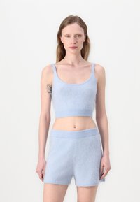 Svetlomodrý pletený crop top s nastaviteľnými ramienkami a zodpovedajúcimi šortkami, ktorý sa vyznačuje jemnou textúrou a rebrovanými detailmi na leme.