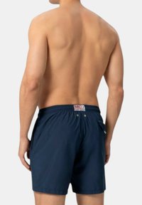 Costume da bagno blu navy con vita elasticizzata, cordoncino e due tasche laterali, caratterizzato da un piccolo etichetta con logo sul retro.