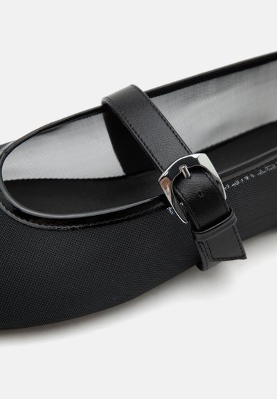 Chaussure Mary Jane noire en tissu texturé, avec une bride lisse à boucle et un détail de boucle métallique argentée brillante.