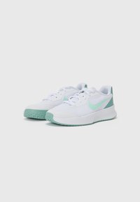 Biele športové topánky s svetlozelenými akcentmi, sieťovaná horná časť, textúrovaná gumová podrážka a šnúrkový uzáver. Obsahujú logo Nike swoosh.