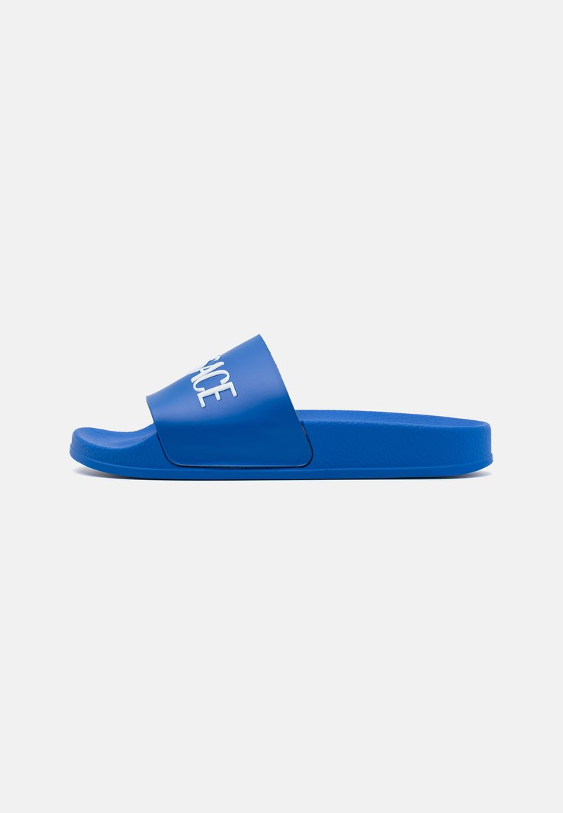 Blaue Rutschen-Sandalen mit einem breiten Riemen, der weißen Text trägt. Sie bestehen aus glattem Kunststoff, haben ein konturiertes Fußbett und eine flache Sohle.