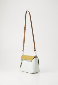 Somu ar piparmētru zaļo ķermeni un teksturētu sinepju dzelteno vāku, ar sudraba rāvējslēdzēju un brūnu regulējamu siksnu.