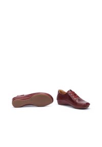 Zapatos de cuero rojo con punta redondeada, costuras decorativas y cordones elásticos. Suela de goma texturizada para agarre y comodidad.