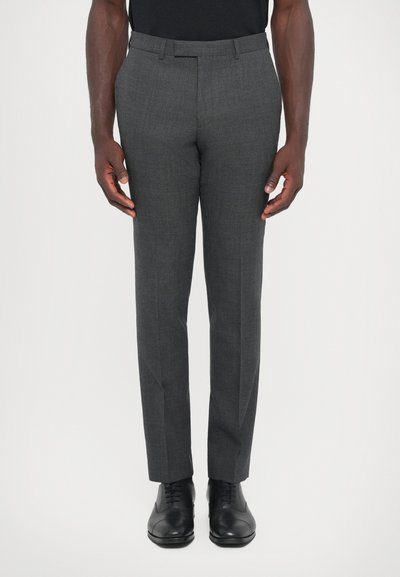 Pantalons gris sur mesure en tissu texturé, présentant une coupe slim, une taille plate et des poches standard, associés à des chaussures de ville noires.