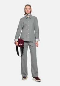 Graues Nadelstreifenshirt und passende Hose, kombiniert mit einer burgunderfarbenen Handtasche. Das Shirt hat einen Kragen und Knöpfe; die Hose ist weit geschnitten.