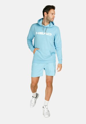 Felpa blu chiaro con logo bianco "HEAD", tasca a marsupio, abbinata a pantaloncini coordinati. Il modello indossa scarpe e calze sportive bianche.