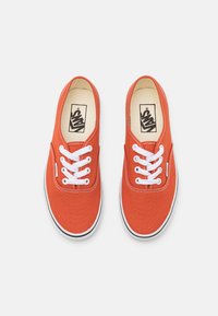 Sneakers in tela rossa con lacci bianchi, punta arrotondata e suola in gomma nera. Presentano un logo sulla soletta e dettagli cuciti sulla tomaia.