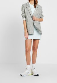 Marynarka w kratę w jasnoszarym i niebieskim kolorze, połączona z pastelowoniebieską sukienką i białymi sneakersami. Posiada luźny krój oraz podwinięte rękawy.