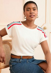 Balta trumpa rankovėmis marškinėliai su spalvingais raudonais, turkio ir tamsiai mėlynos spalvos dryžiais ant pečių. Minkšta medžiaga, laisvas kirpimas.