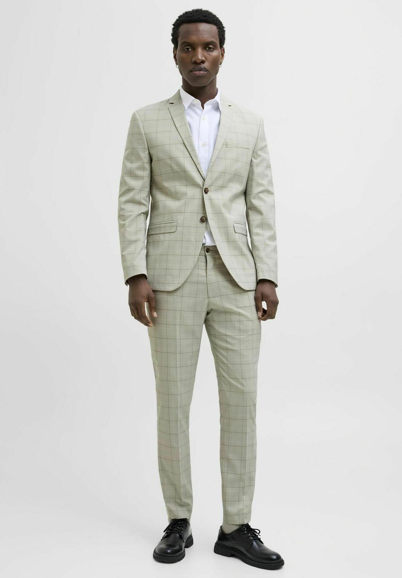Lichtgroen geblokt pak met een enkelgebreide jas en slim-fit broek. Gecombineerd met een wit shirt en zwarte schoenen. Soepele stoftextuur.