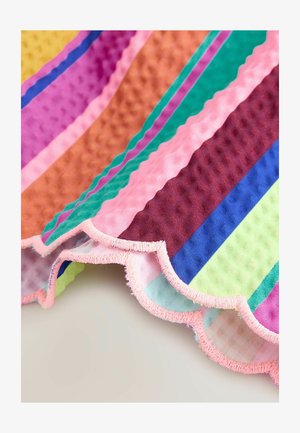 Večbarvna tkanina z navpičnimi črtami in teksturirano površino, z valovitimi robovi in rožnato nazobčanim obrobkom. Barve vključujejo zeleno, vijolično in oranžno.