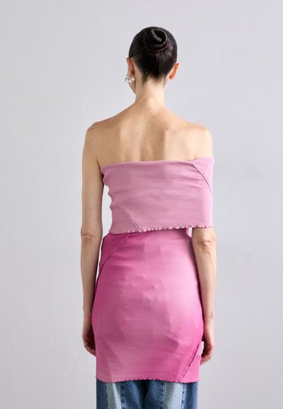 Rosa geripptes Off-Shoulder Kleid mit taillierter Form, das einen Farbverlaufseffekt und rohe Kanten aufweist. Stilisiert mit hoch geschnittenen Jeans.