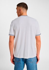 White short-sleeve t-shirt with a rounded neckline, featuring navy stripes on the sleeves. Cotton material with a smooth texture.