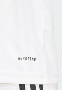 Vit sportt-shirt med platt krage och en liten svart "AEROREADY"-logotyp på vänster sida, gjord av strukturerad tyg.