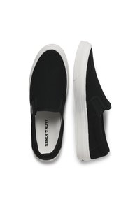 Fekete slip-on tornacipők fehér gumitalppal, vászon felsőrésszel, elasztikus oldalsó panelekkel és márkázott talpbetéttel. Sima felület, minimalista dizájn.
