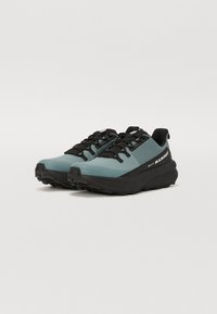 Gore-Tex hardloopschoenen met een lichtblauwe bovenkant, zwarte veters en een buitenzool met een robuust loopprofiel voor grip. Merklocatie zichtbaar aan de zijkant.