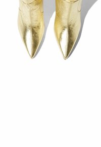 Zlatne metalik čizme do gležnjeva s dizajnom u obliku špica i glatkom teksturom, karakteriziraju ih elegantna silueta i minimalni detalji.