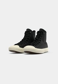 Sneakers nere alte con tomaia in canvas, punta in gomma e suola bianca testurizzata. Presentano lacci neri e dettagli del logo laterale.