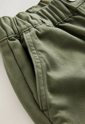 Olivgrüne Baumwollshorts mit strukturiertem Finish, ausgestattet mit einem elastischen Bund und Seitentaschen, aus einer Nahaufnahme gezeigt.