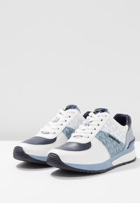 Baskets blanches et bleu marine avec un motif texturé bleu, des matériaux contrastés, un bout rond, des lacets blancs et une semelle rembourrée.