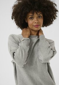 Gray, knit sweater with long sleeves, ribbed cuffs, and a relaxed fit. Notable texture and softness visible in the fabric.