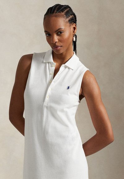 Biała sukienka polo bez rękawów z kołnierzykiem i trzema guzikami. Z haftowanym logo na piersi i gładką, teksturowaną tkaniną.