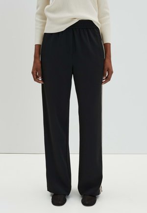 Black wide-leg pants with an elastic waistband, featuring side stripes and soft fabric, paired with a cream ribbed sweater.