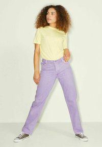 Jeans de ganga roxos combinados com uma t-shirt amarela clara. Os jeans apresentam um corte de perna reta, enquanto a t-shirt tem um decote redondo.