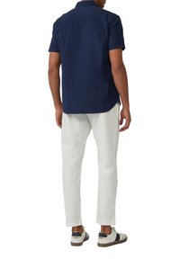 Kurzärmliges navy Hemd mit Button-Down-Kragen, kombiniert mit weißen Hosen und lässigen Sneakers, zeigt einen lockeren Sitz und klare Linien.