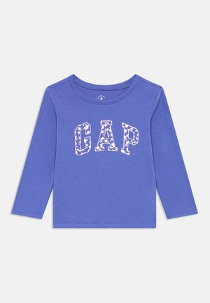 Camicia a maniche lunghe viola con collo rotondo. Presenta il logo "GAP" in uno stile a motivi bianchi. Tessuto di cotone morbido e elasticizzato.
