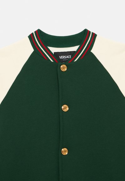 Πράσινο και κρεμ μπουφάν μπέιζμπολ με ριμπάτο γιακά που φέρει κόκκινες και πράσινες ρίγες, χ ρυσά κουμπιά και ετικέτα Versace.