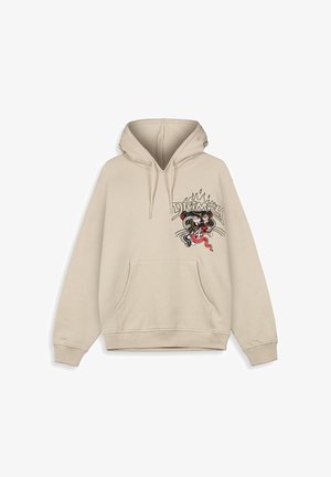 Beige hoodie met een voorzak, een trekkoordkap en een geborduurde tijgerontwerp aan de linkerkant, met gedurfde kleuren en details.