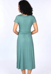 Kurzärmliges, knöchellanges Kleid aus grünem Stoff mit einem wiederholten blauen Muster. Glatte Textur, taillierter Schnitt und lockerer Rock.