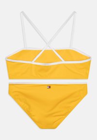 Yellow bikini with white straps. Top features a bandeau design with crisscross straps, bottom has a small logo detail in the center.