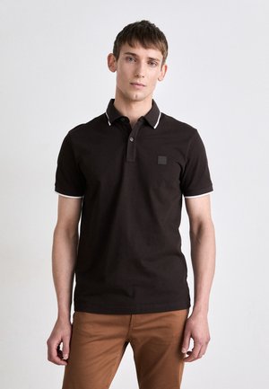 Black polo shirt with white trim on the collar and sleeves, featuring a small logo patch on the chest and a classic button closure.