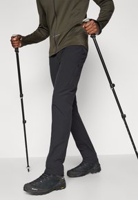 Ανδρικό παντελόνι εξωτερικού χώρου σε μαύρο χρώμα, φτιαγμένο από ελαφρύ, ελαστικό υλικό. Διαθέτει πλαϊνές τσέπες με φερμουάρ και ενισχυμένα ράμματα για μεγαλύτερη αντοχή.