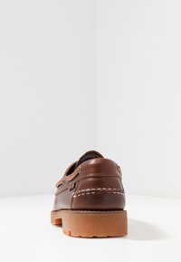 Braunes Leder Schuh mit rundem Design, Kontrastnähten, Gummisohle und seitlichen Schnürdetails. Texturierte Oberfläche im Obermaterial.