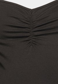 Tecido preto com uma textura pregueada ao centro, criando uma subtil forma de V. O material parece elástico e suave.