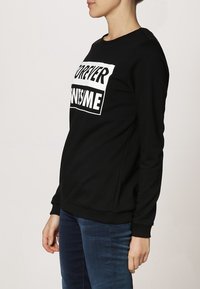 Černá mikina s dlouhými rukávy, která má odvážný bílý potisk se slovy "NAVŽDY ÚŽASNÝ." Stylová s volným střihem a žebrovanými manžetami.