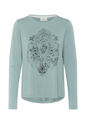 Lichtblauw langslivig T-shirt van zachte stof met een zwart ingewikkeld mandala-patroon op de voorkant, een gebogen zoom en een ronde hals.