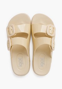 Tan plastic sandals with two wide straps featuring rectangular buckles, textured footbed, and oval-shaped sole. Logo visible on footbed.