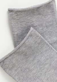 Calcetines grises de punto con una textura acanalada, que presentan un acabado suave y un diseño simple en la parte superior. No hay patrones o acentos distintivos.