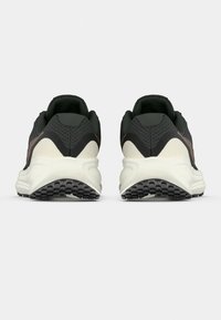 Crne i maslinasto zelene atletske cipele s teksturiranom gornjom površinom, kontrasnom kremastom srednjom potplate i gumenim potplatom. Minimalistički dizajn s glatkim linijama.