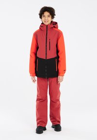 Rot-schwarze Skiausrüstung mit Kapuze, ausgestattet mit Reißverschlusstaschen und tailliertem Design. Enthält wasserdichte Hose und robuste Schuhe.