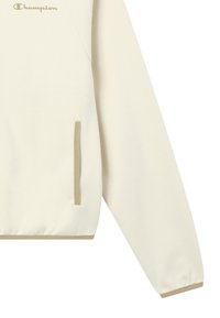 Felpa color crema realizzata in tessuto morbido. Presenta un design raglan, una tasca a marsupio e accenti beige su polsini e orlo.