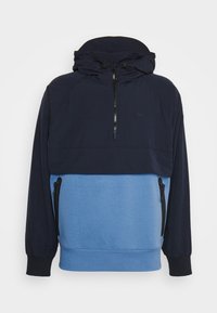 Sweatshirt med huva som har en marinblå överdel och en ljusblå underdel. Materialet har en mjuk yta, med dragkedja och sidfickor.