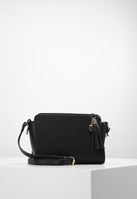 Borsa a tracolla nera in ecopelle, con forma rettangolare, tracolla regolabile e dettagli in hardware dorato con una frangia.