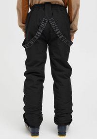 Pantalons de neige noirs avec une coupe décontractée, dotés de bretelles ajustables avec le texte "NORTH BEND", et en tissu texturé pour une durabilité accrue.